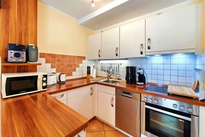 A modern kitchen with a microwave, toaster, coffee maker, and stove. - Pinguin Vacation Rental – Where Nature, a Sauna, and the Sea Await You - Küstenwaldhaus (Koserow)