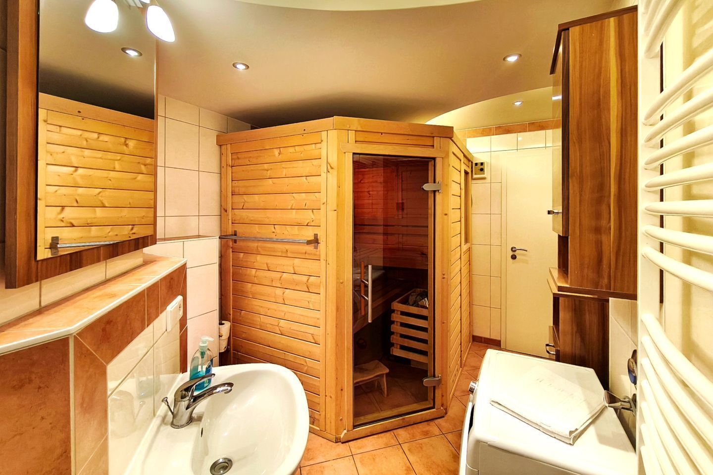A bathroom with a wooden shower enclosure, a sink, and a toilet.