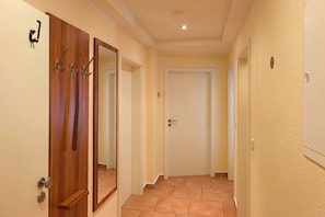 A hallway with a wooden door, a mirror, and a white door at the end. - Pinguin Vacation Rental – Where Nature, a Sauna, and the Sea Await You - Küstenwaldhaus (Koserow)