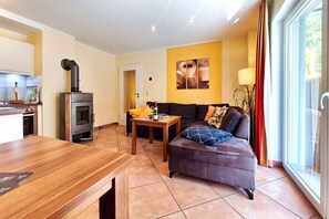 Ein modernes Wohnzimmer mit einer Couch, einem Esstisch und einer Küchenzeile mit Herd.