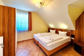 Ein Schlafzimmer mit Holz-Kopfstütze, einem Bett mit weißen Leinen, einem Nachttisch, einer Wandlampe und einem Fenster mit Vorhängen.