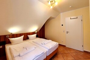 A hotel room with two beds, a wooden headboard, a door with a handle, and a ceiling light fixture. - Seepferdchen Vacation Rental – Relaxation in the Coastal Forest, Just 550 m from the Beach - (Koserow)