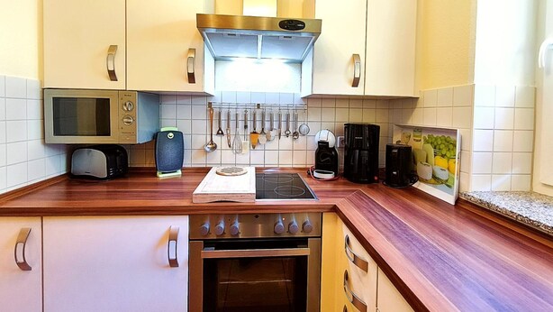 A kitchen with a microwave, toaster, coffee maker, and a gas stove. - Möwe Vacation Rental – Relaxation Between the Forest and the Baltic Sea - Küstenwaldhaus (Koserow)