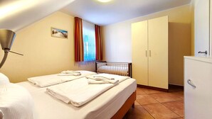 Une chambre d’hôtel avec un lit, un radiateur, une armoire et une fenêtre avec des rideaux.