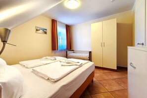 Ein Hotelzimmer mit Bett, Heizkörper, Schrank und einem Fenster mit Vorhängen.
