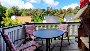 Une terrasse avec une table ronde et quatre chaises, entourée d’une balustrade blanche.