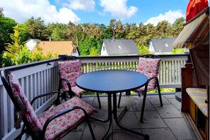 Eine Terrasse mit einem runden Tisch und vier Stühlen, umgeben von einem weißen Geländer.