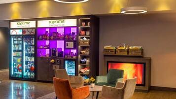 A modern lobby with two refrigerated display cases labeled 'KUKIME,' a fireplace, and seating area with chairs.