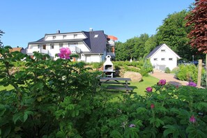 A residential area with houses, a barbecue grill, and a picnic table. - Küstenwaldhaus "Muschel" Vacation Rental – Relaxation Between the Forest and the Baltic Sea - (Koserow)