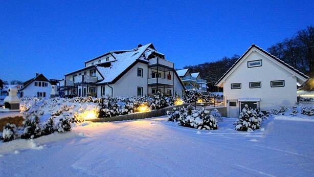 Ein Wohngebiet mit schneebedeckten Häusern und einem gut beleuchteten Weg.