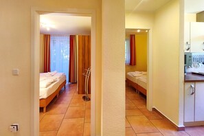 A hotel room with two beds, a kitchenette, and a bathroom visible through an open door. - Seestern Vacation Rental: Sauna, Fireplace & 550 m to the Baltic Sea Beach - Küstenwaldhaus (Koserow)