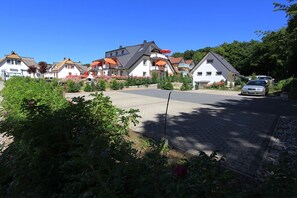Eine Wohnstraße mit Häusern, einem gepflasterten Einfahrt und einem parkenden Auto.
