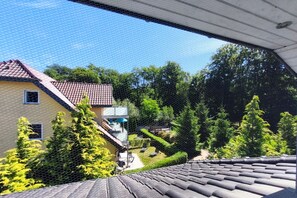 Ein Wohngebiet mit einem Haus, das ein rotes Ziegeldach, einen Balkon und einen Garten mit verschiedenen Pflanzen hat.
