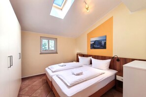 Ein Hotelzimmer mit Bett, Fenster, einem Bild an der Wand und einem Oberlicht.