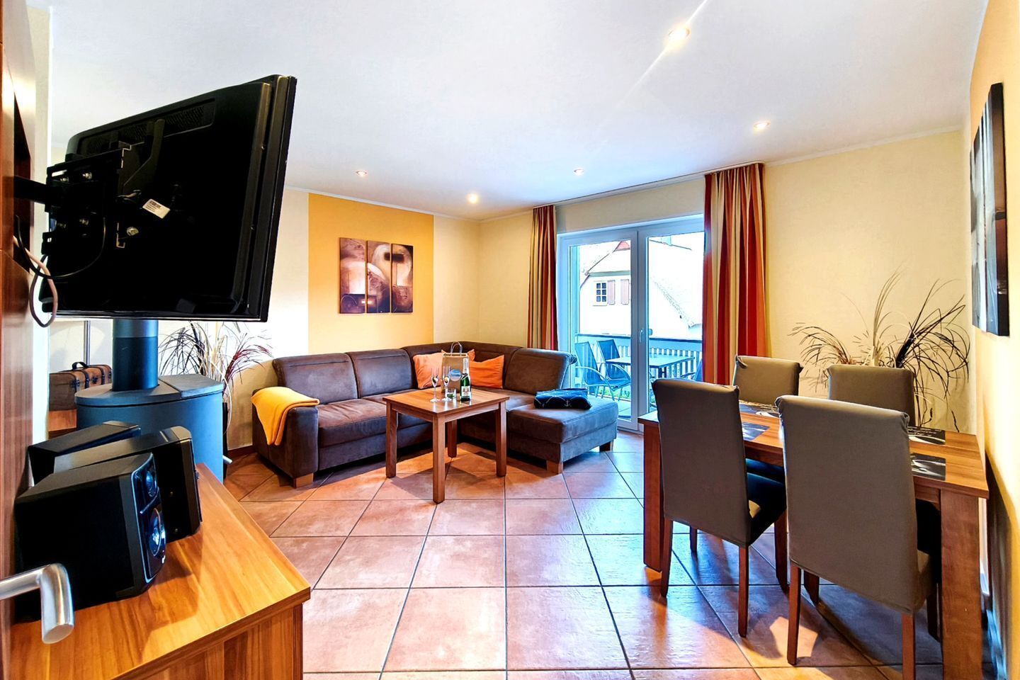 A living room with a sofa, coffee table, and chairs, a television, and a dining area with a table and chairs.
