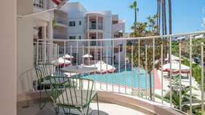 A balcony with a pool, green chairs, and umbrellas. - Villa Coo (Kos)