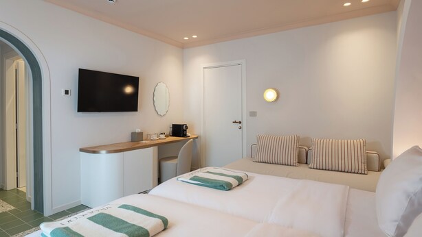 A hotel room with a bed, a desk, a TV, and a door. - Villa Coo (Kos)