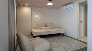 A modern, minimalistic room with a sofa, a chair, and an air conditioning unit. - Villa Coo (Kos)