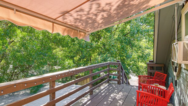 A wooden deck with a railing, a covered area with a beige canopy, and red chairs. - Walk to Downtown Chico! Tree-Lined Apt w/ Deck (Chico)