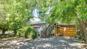A covered outdoor area with a wooden bench, a red umbrella, and a staircase leading to a building. - Walk to Downtown Chico! Tree-Lined Apt w/ Deck (Chico)
