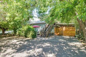 A covered outdoor area with a wooden bench, a red umbrella, and a staircase leading to a building. - Walk to Downtown Chico! Tree-Lined Apt w/ Deck (Chico)