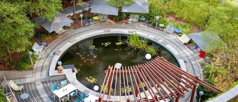 A circular outdoor area with a pond, seating, and umbrellas.