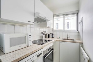 Eine moderne Küche mit weißen Schränken, einer eingebauten Mikrowelle, einem Kochfeld und einem Geschirrspüler.