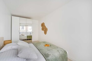 Ein Schlafzimmer mit einem Bett, einer grünen Decke, einem kleinen Tisch mit Essen und einem Schrank sowie einem Spiegel.