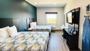 A hotel room with two beds, a desk, a TV, and a window with a view.
