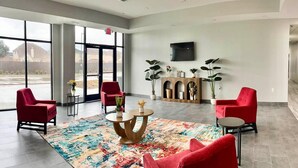 A spacious lobby with large windows, red chairs, a central round table, and a flat-screen TV mounted on the wall. - 2 Queen Beds|Non-Smoking,Kitchen (Houston)