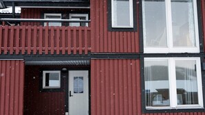 Un edificio de dos plantas con fachada roja, una puerta blanca y un balcón.