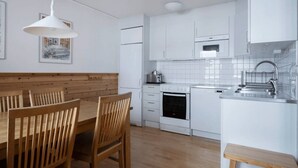 Una cocina moderna con armarios blancos, una mesa de comedor de madera y una lámpara colgante.