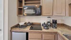 A compact kitchen with a built-in microwave, a refrigerator, and a coffee maker. - Peace Of Mind Rentals (Plaquemine)