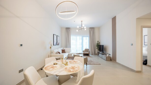 Un soggiorno moderno con zona pranzo, divano, televisore e lampadario.