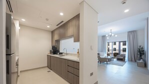 Una cucina moderna con forno a incasso, macchina del caffè e lavello. C'è un'area pranzo con un divano e un tavolino.