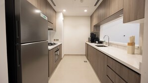 Una cucina moderna con elettrodomestici in acciaio inossidabile, mobili in legno e un piano di lavoro bianco.