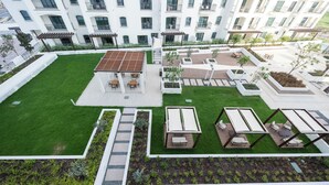 Un giardino pensile con zone relax, una pergola e una piscina.