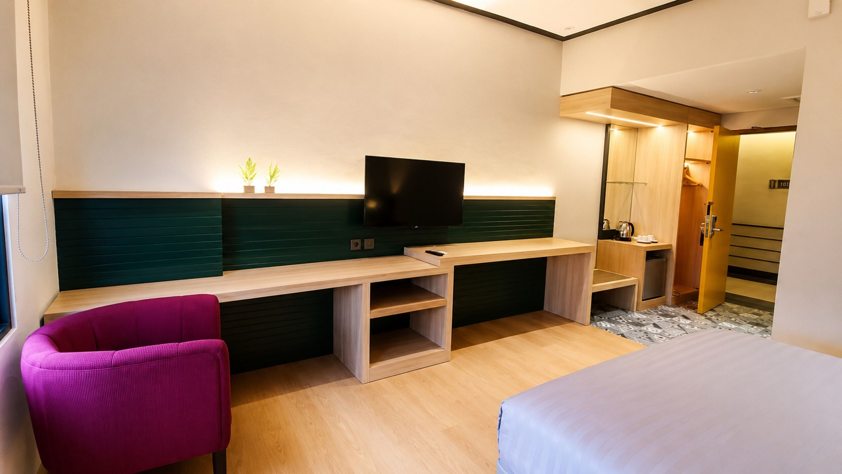 Une chambre d’hôtel comprenant un lit, un bureau avec une télévision, une chaise et une salle de bain.