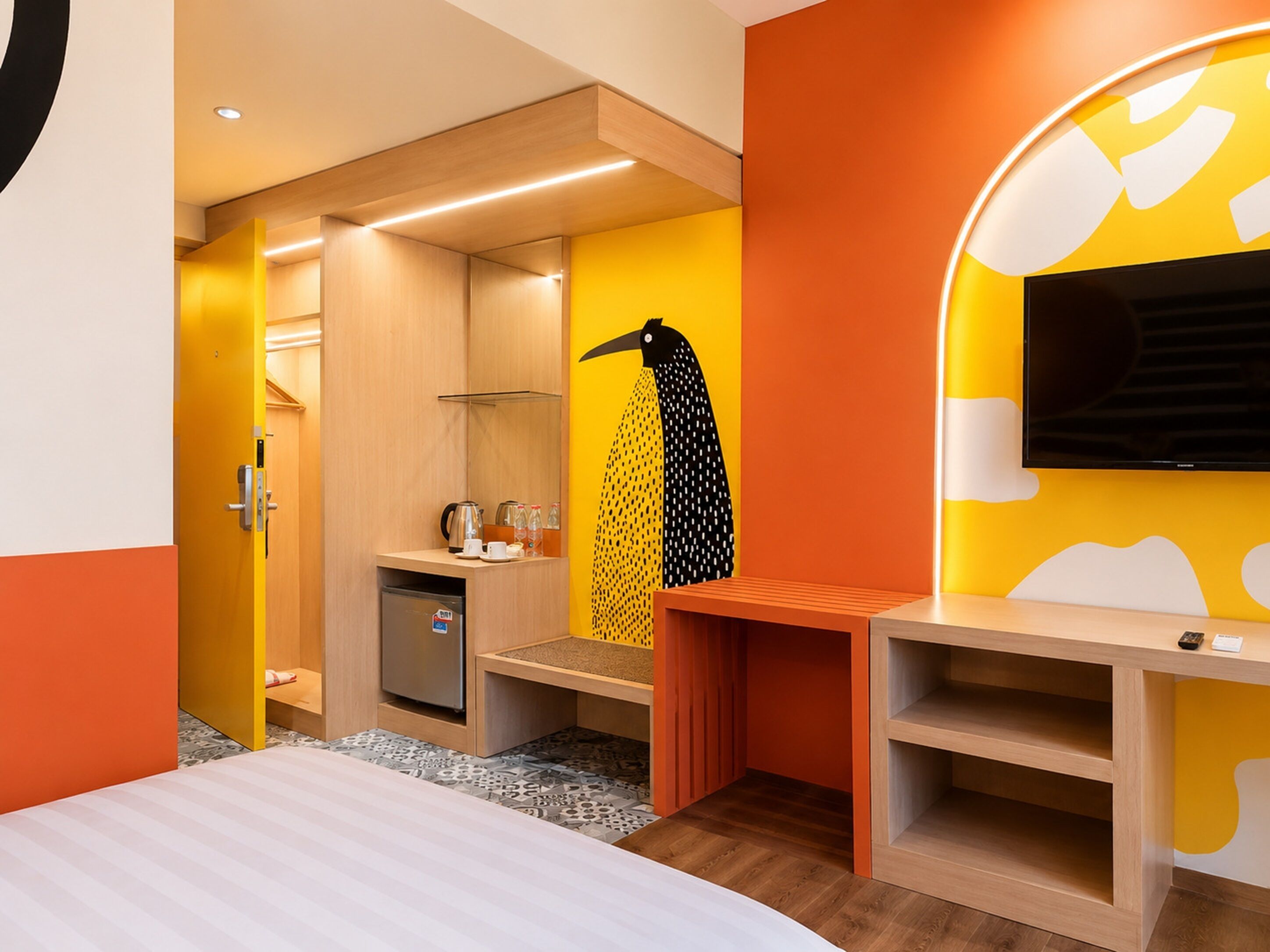 Une chambre d’hôtel moderne équipée d’un lit, d’un bureau, d’une télévision et d’un mini-bar.