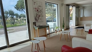 A modern living room with a red sofa, white armchairs, a coffee table, and a dining area with a table and chairs. - Baia di Tempsa Beach and Sea (Amantea)