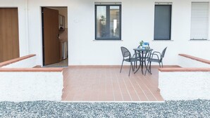 Eine Terrasse mit Tisch und Stühlen, einer Tür und einem Fenster.