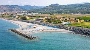 Una zona costanera amb una platja, un litoral rocos i una serralada llunyana.