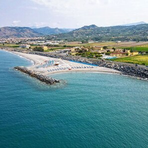 Eine Küstenlandschaft mit Strand, felsigem Ufer und einer entfernten Bergkette.