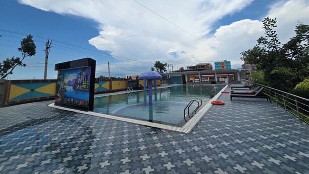 An outdoor swimming pool with a tiled deck, a lifeguard stand, and a mural.