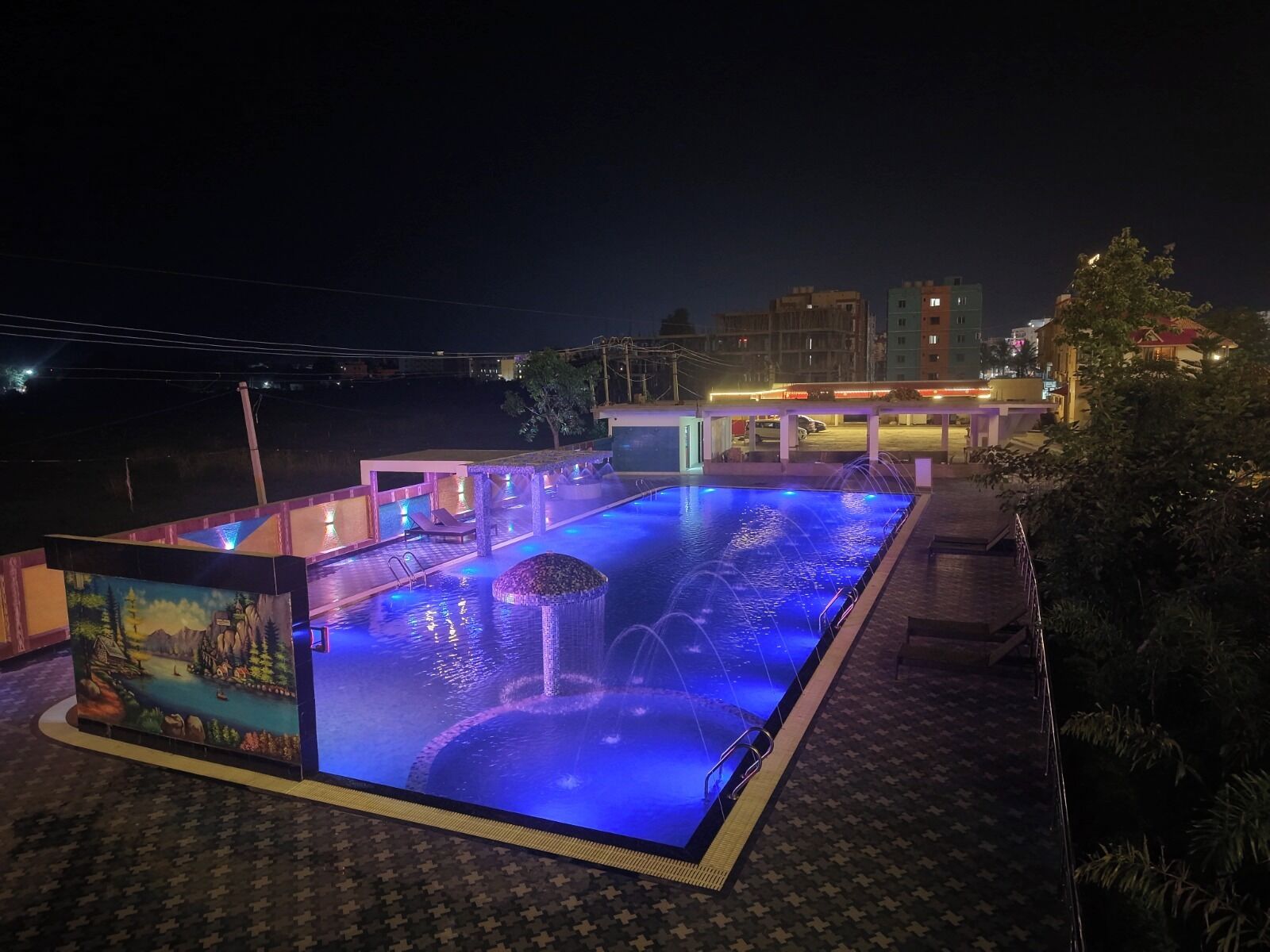 Ein Schwimmbecken mit Wasserspiel bei Nacht.