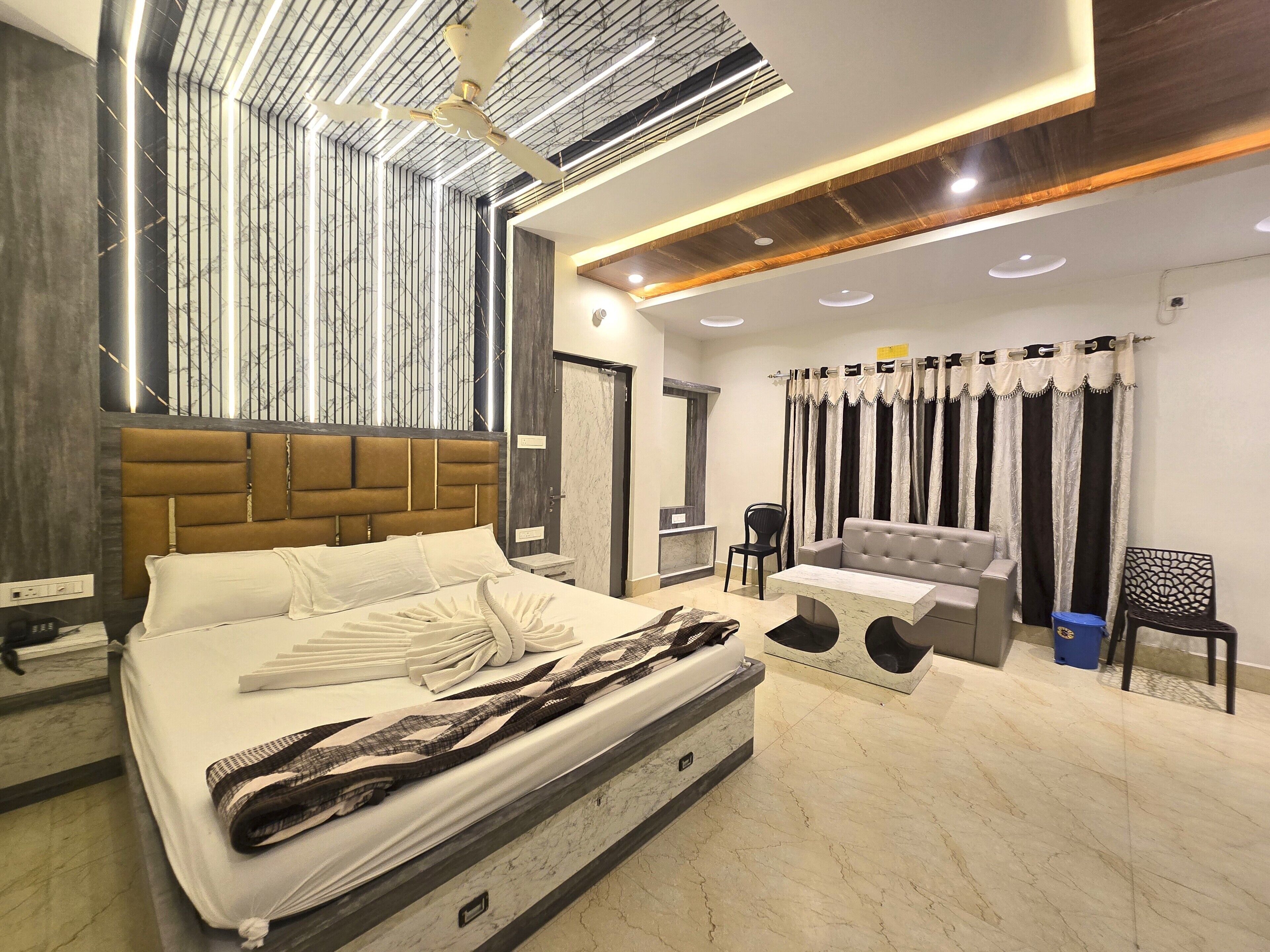 A modern bedroom with a large bed, a sofa, a chair, and a small table.