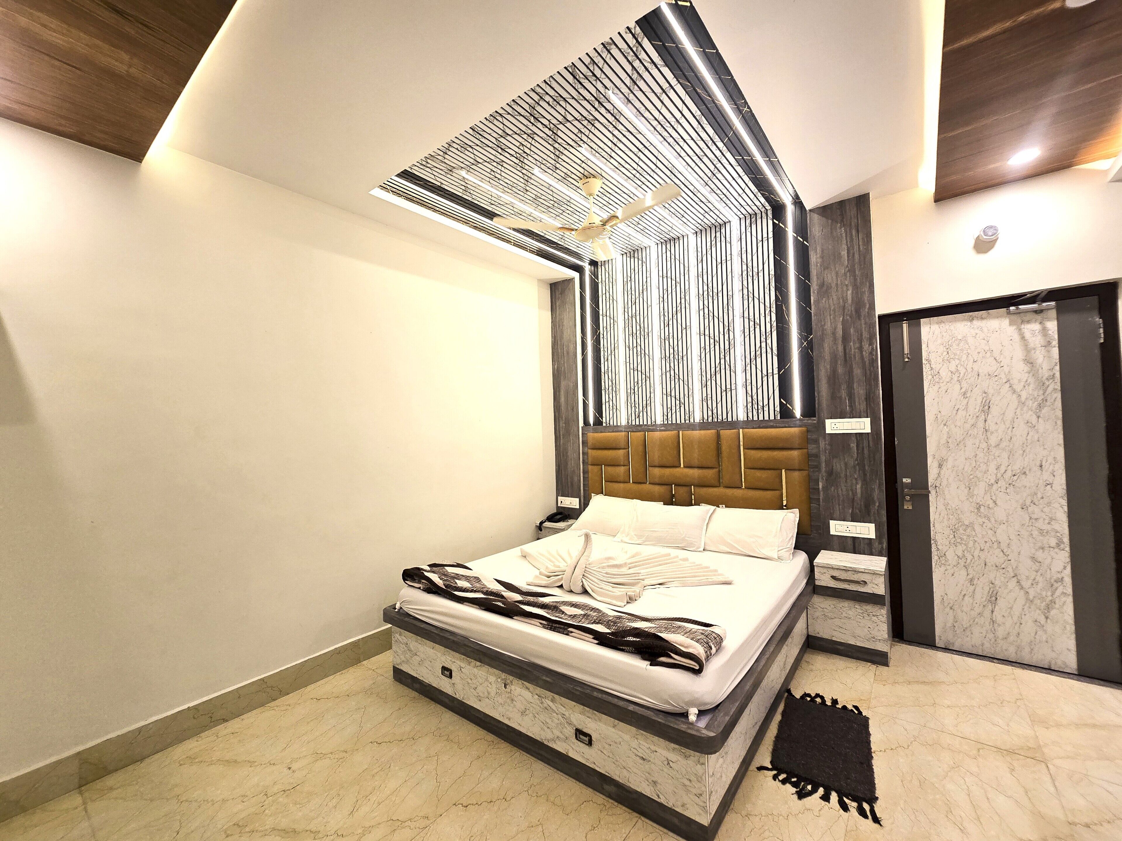 A modern bedroom with a bed, a ceiling fan, and a door.