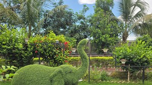 A topiary elephant in a lush garden with various plants and a clear sky.