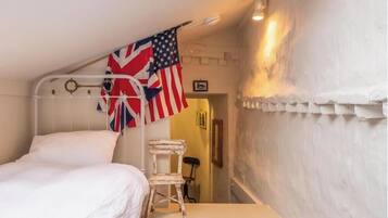 A room with a bed, a chair, and two flags.