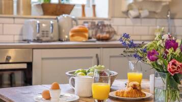 Um café da manhã com ovos, suco, croissants e uma saladeira de frutas.